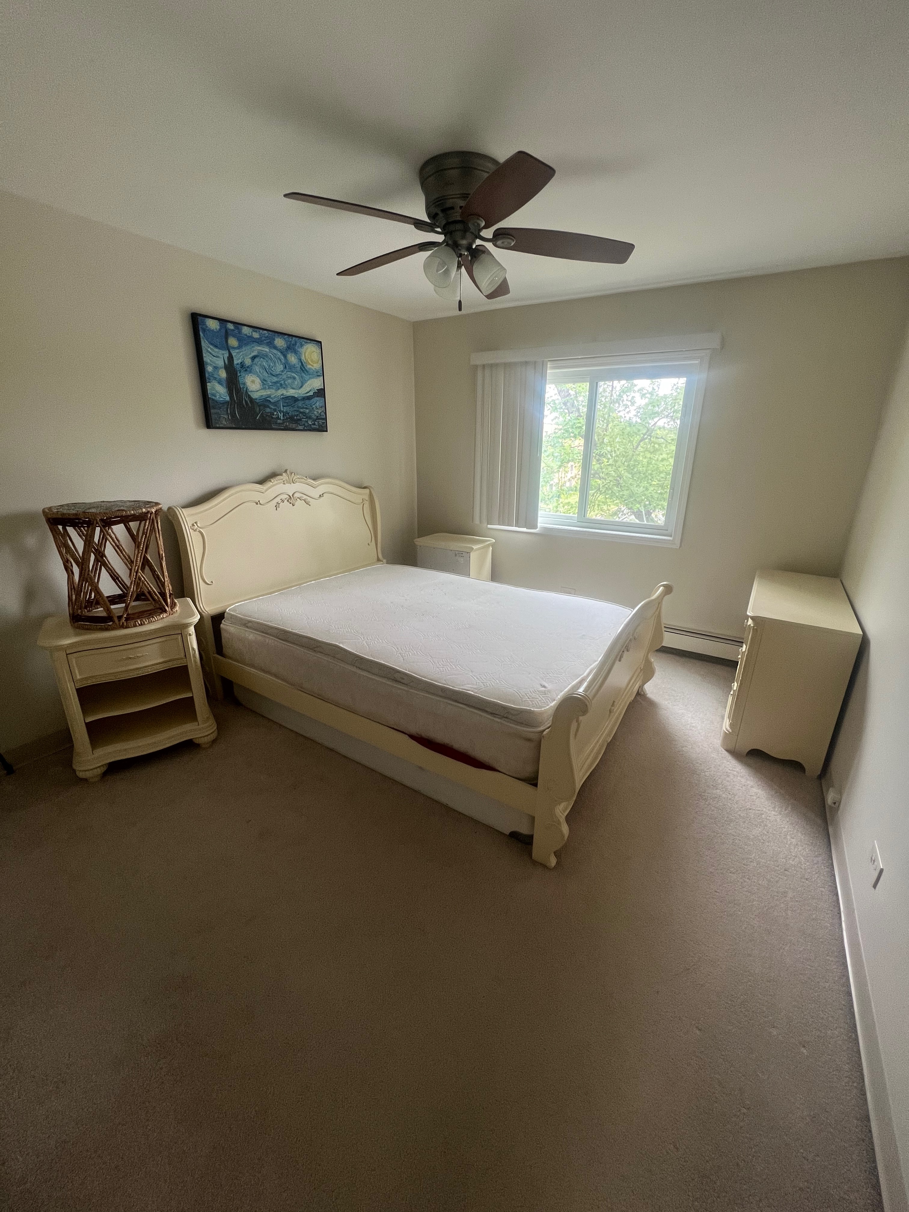 Calgary, Alberta, Canada. Jun 8, 2025. A sunlit garage stands open, revealing a clutter of household items, storage bins, hinting at a need for organization.